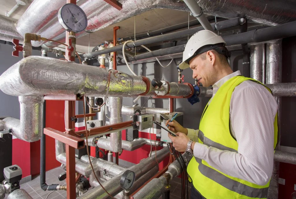 Man in helmet writing down measurements in heat and aircondition