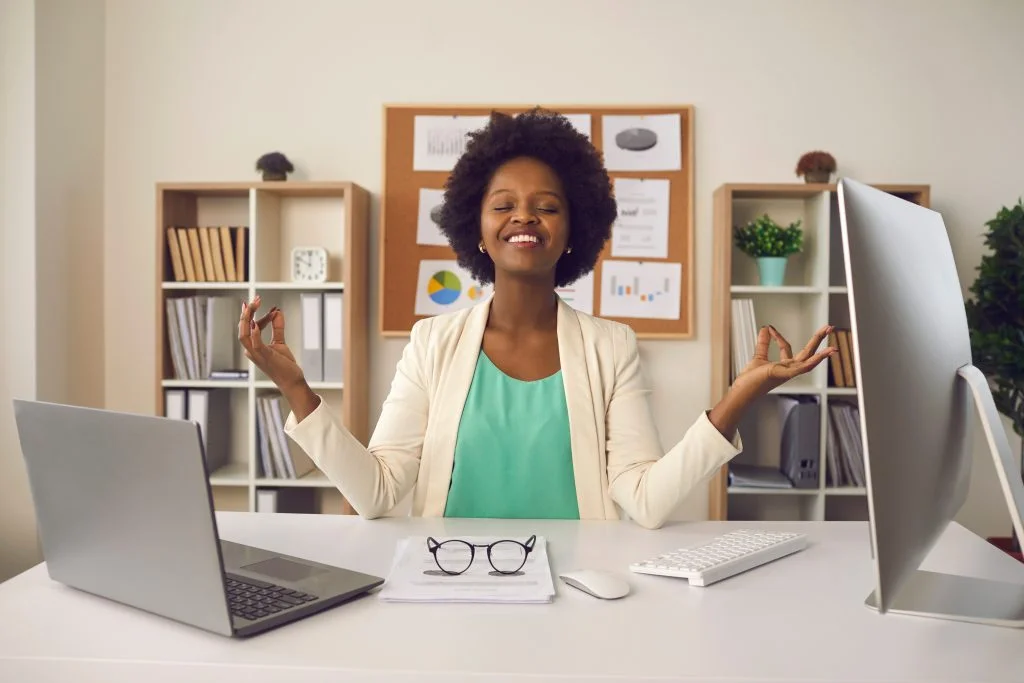 Young woman sitting at office desk and meditating focusing only on positive emotions